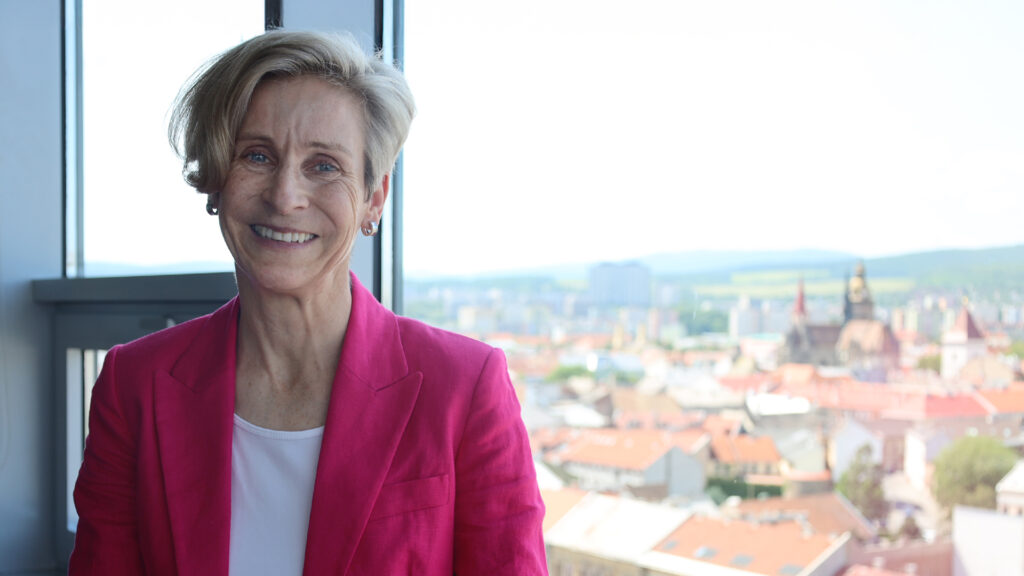 Stefanie steht im CANCOM Büro vor einem Fenster. Im Hintergrund sieht man Košice.