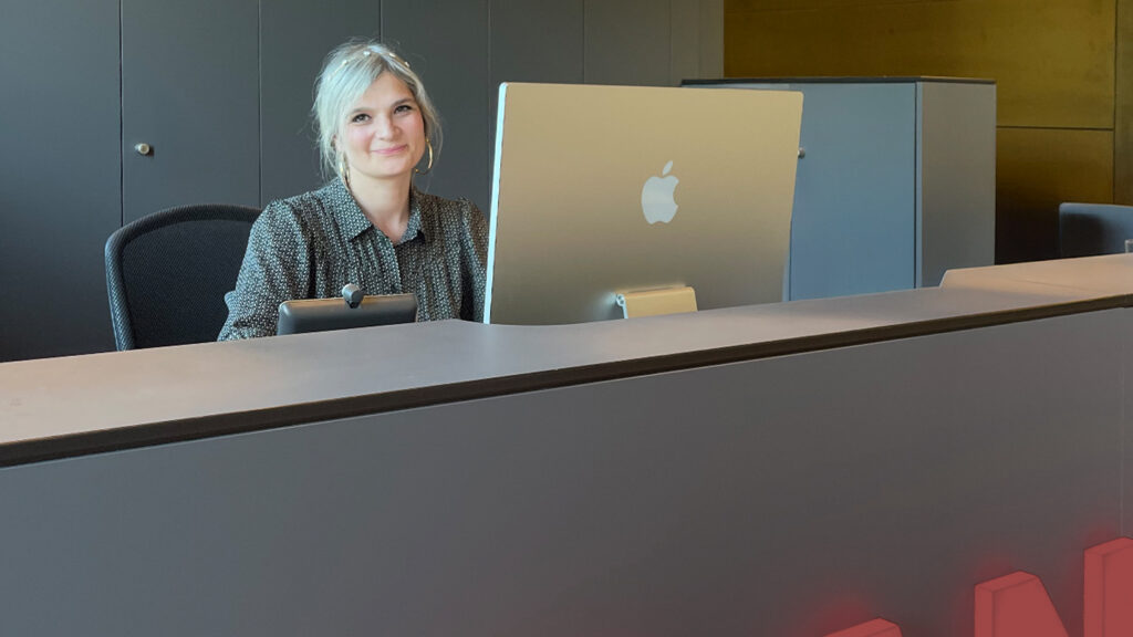 Jessica sitzt vor ihrem Bildschirm am CANCOM Empfang.